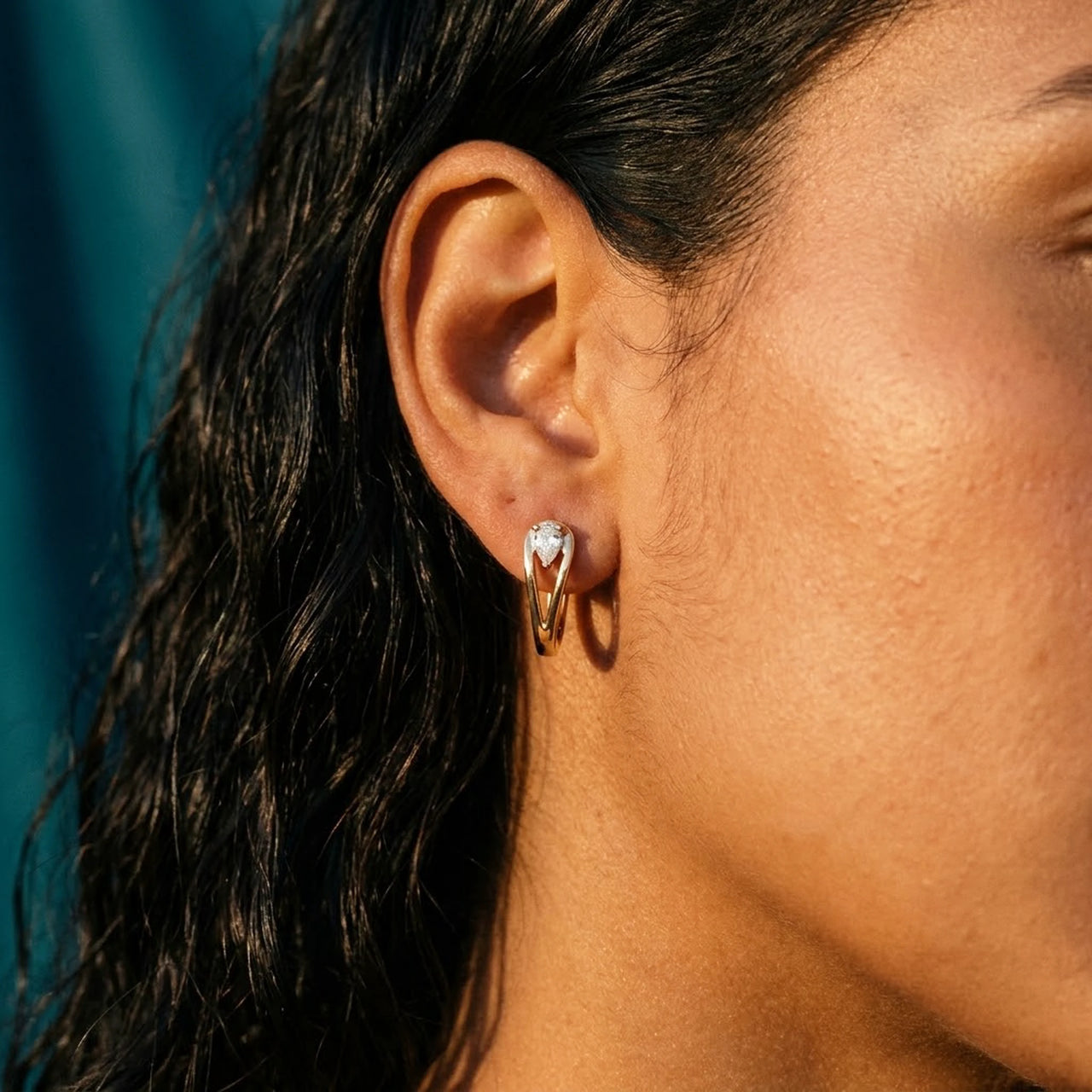 Pear Crystal Huggie Hoops in Gold, close-up on the earlobe | SKU: 41007-gold