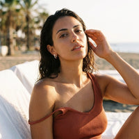 Thumbnail for Pear Crystal Huggie Hoops in Gold, worn at a beach club at sunset | SKU: 41007-gold