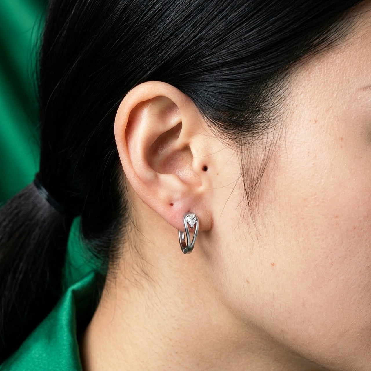 Pear Crystal Huggie Hoops in Silver, close-up on the earlobe | SKU: 41007-silver