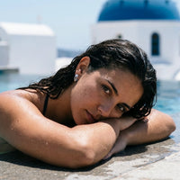 Thumbnail for Pear Crystal Huggie Hoops in Silver, worn by a pool in Santorini | SKU: 41007-silver
