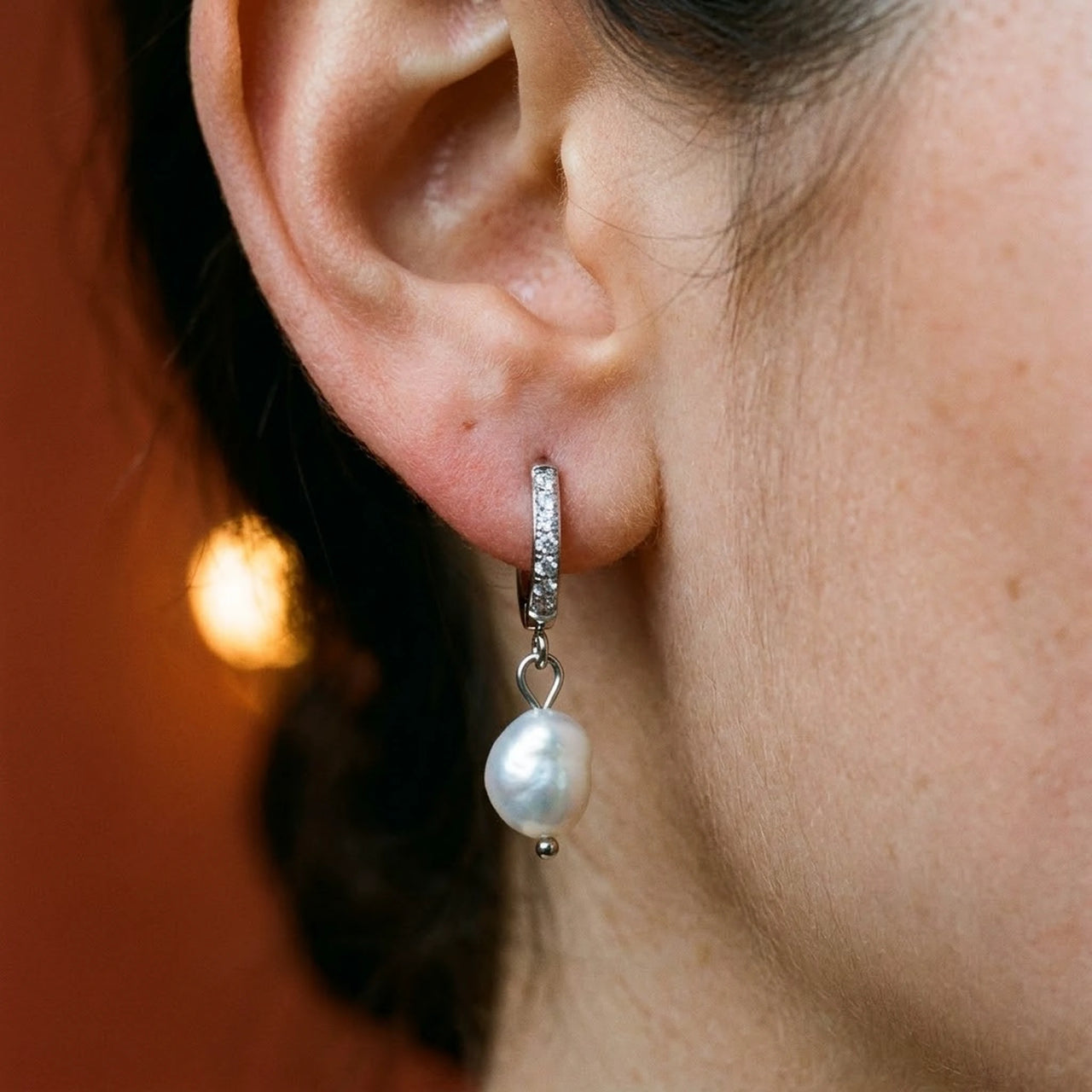 Pearl Drop Huggie Hoops in Silver, close-up on the earlobe | SKU: 41003-silver