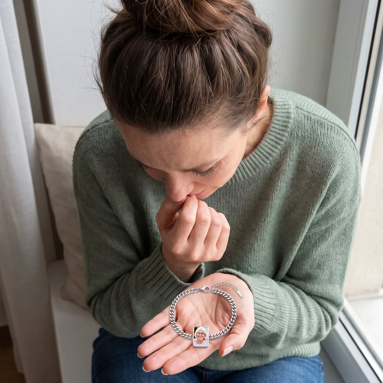 Moved woman looking down at the silver Secret Cushion Photo Bracelet in her palm, her grandmother's photo revealed in the plate | SKU: TPH-CUSB-SILVER