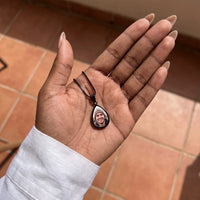 Thumbnail for The black teardrop photo pendant in an open palm over terracotta tiles, showing its real small size | SKU: TPH-DRPN-BLACK