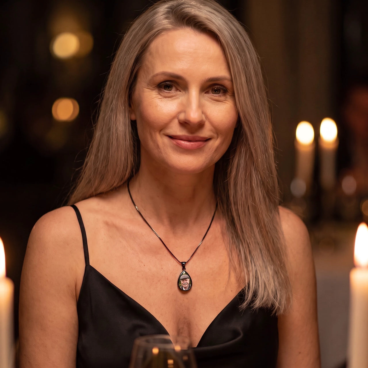 Woman in a black dress at a candlelit dinner wearing the black secret drop photo necklace | SKU: TPH-DRPN-BLACK
