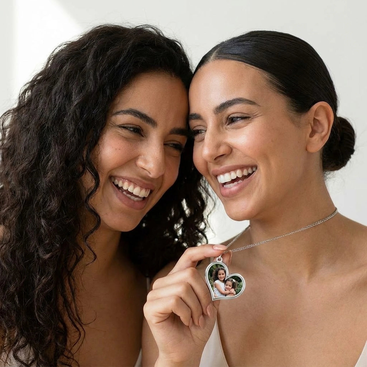 Two sisters laughing over their childhood photo hidden in the silver heart necklace | SKU: TPH-HRTN-SILVER